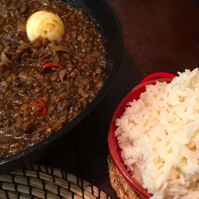 Kik Wat stew served in a pan beside a bowl of fluffy white rice