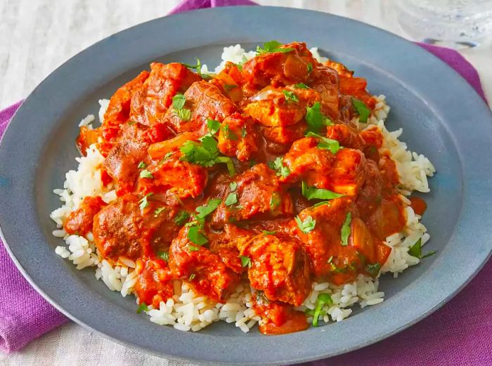 An overhead shot of a plate with rice topped with flavorful chicken tikka masala.