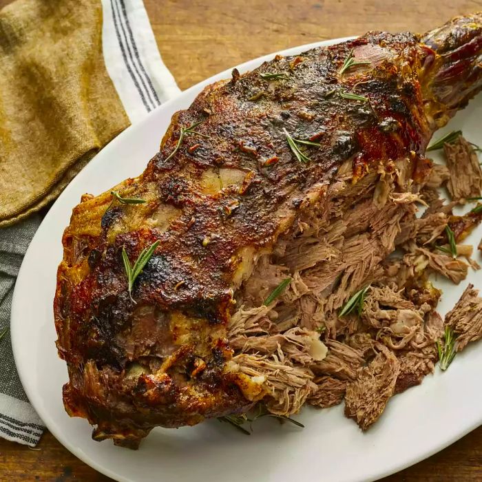 A high-angle view of a platter featuring roast leg of lamb with some shredded meat