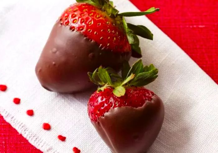 Two homemade chocolate-covered strawberries.