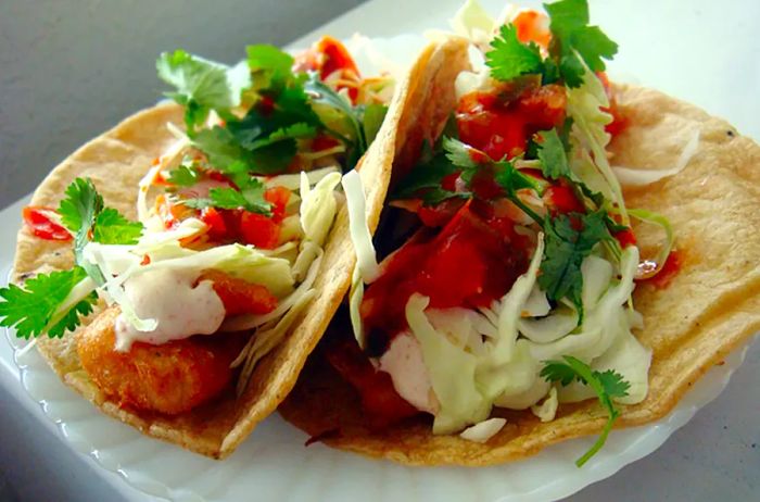 two fish tacos topped with fresh ingredients