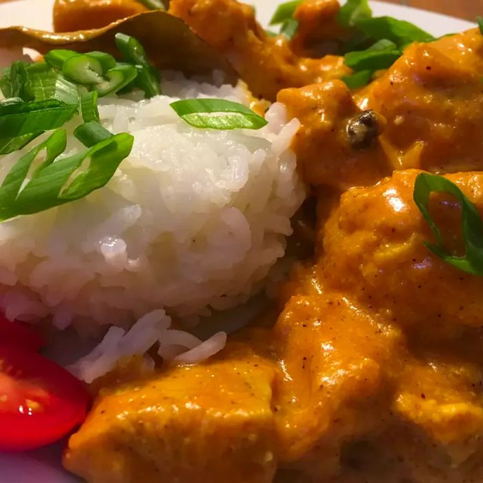 A serving of chicken korma, paired with a side of white rice.