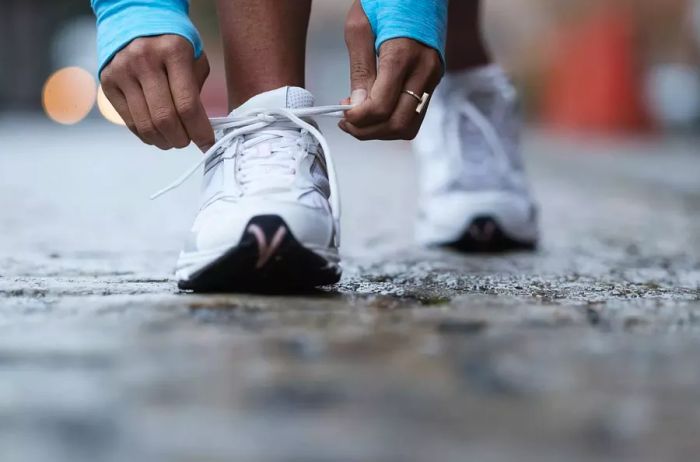 A mixed-race runner tying their shoelaces