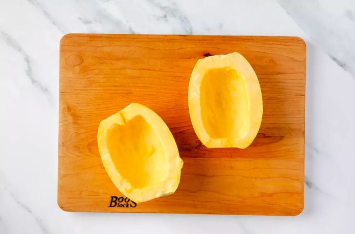 Halved spaghetti squash on a wooden cutting board