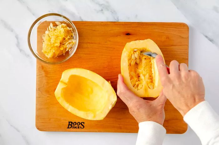 Scooping out the seeds from a halved spaghetti squash