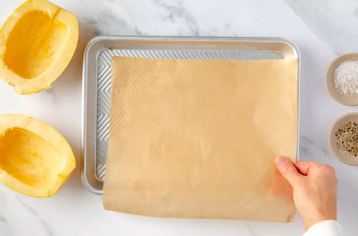 Lining a baking sheet with parchment paper to roast spaghetti squash