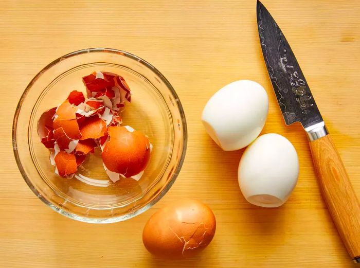 An overhead shot of boiled eggs being peeled, ready to be chopped.