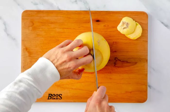 Spaghetti squash being sliced lengthwise on a wooden cutting board