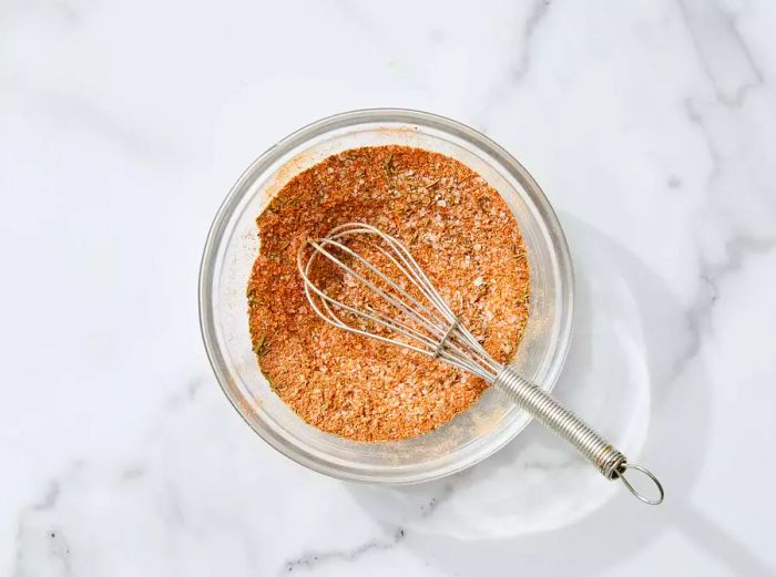 A glass bowl with a whisk holding the spice mixture