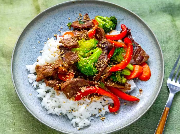 Close-up overhead shot of a single serving of beef stir-fry served over fluffy white rice.