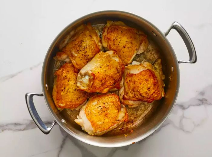 A top-down view of chicken thighs cooking in a pot