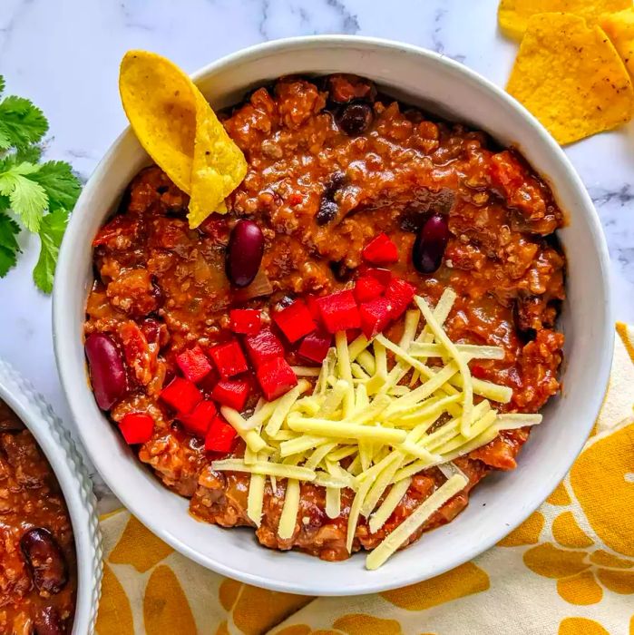 A top-down view of bowls filled with homemade chili, garnished with fresh tomatoes and a sprinkle of shredded cheese.