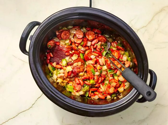 Louisiana Red Beans with meats and vegetables in a slow cooker, served with a spoon