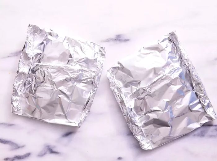 Two tightly sealed foil packets resting on a marble countertop