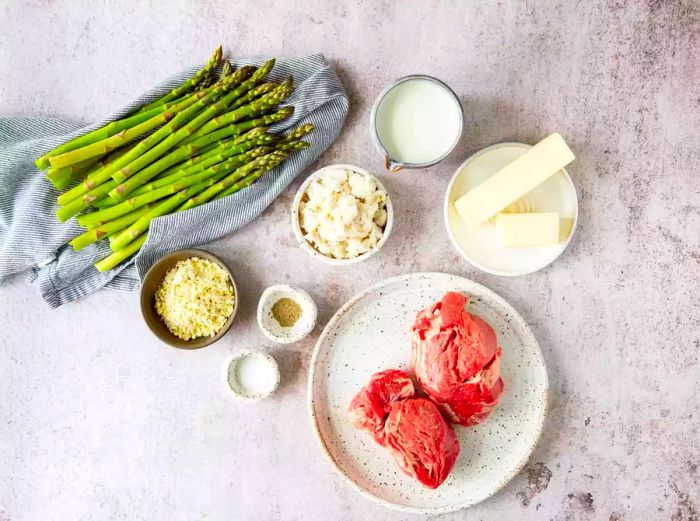 Fresh steak and crisp asparagus with butter and seasonings, ready for preparation.