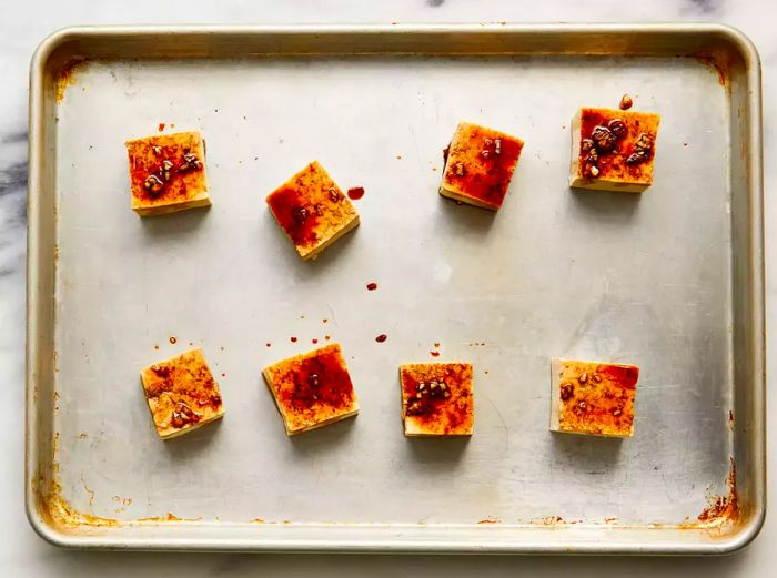 Tofu pieces coated with sauce on a baking sheet