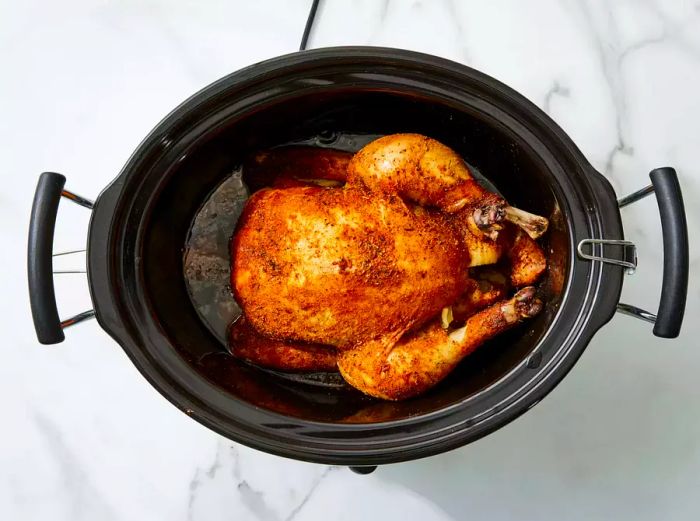 Whole chicken cooking in a slow cooker