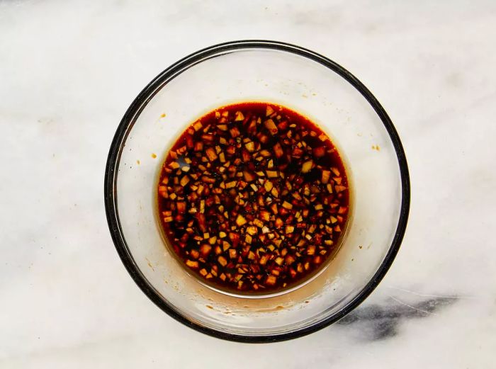 A glass bowl filled with a sauce made from soy sauce, agave, sesame oil, garlic, and ginger