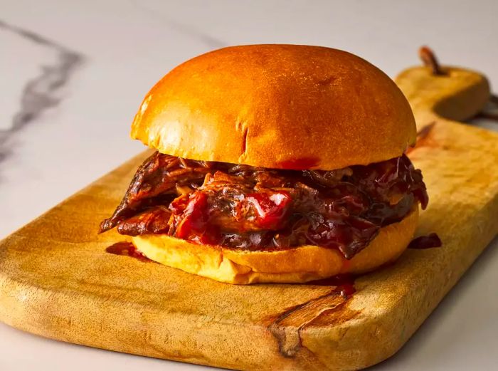 A close-up of slow cooker barbecue nestled in a soft brioche bun.