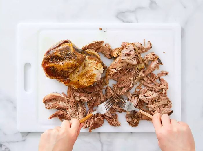 Shredding the tender pork shoulder after 12 hours of slow cooking.