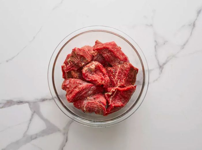 A top-down view of seasoned beef chunks in a bowl