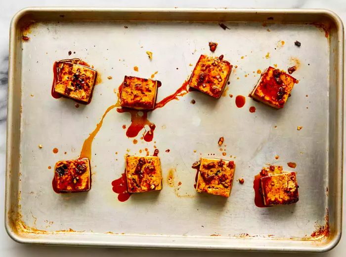 Tofu coated with sauce on a baking sheet