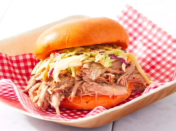 A close-up of a Carolina BBQ pulled pork sandwich, topped with a generous serving of coleslaw.