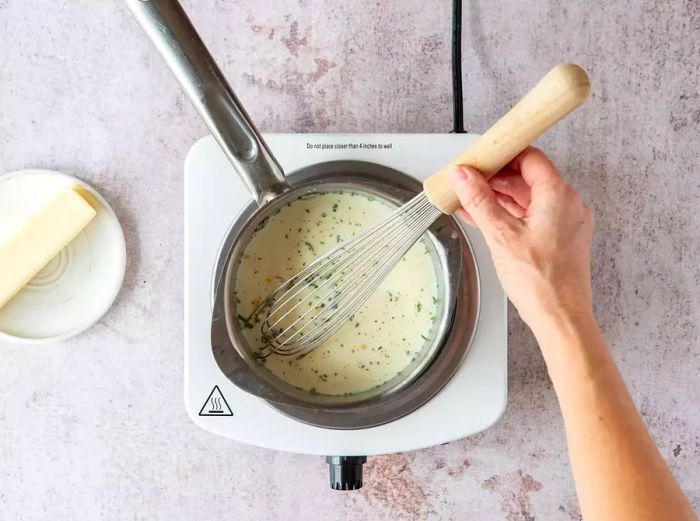 Whisking the butter sauce in the saucepan.