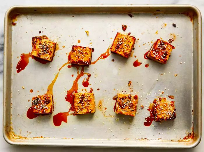 Tofu topped with sesame seeds on a baking sheet