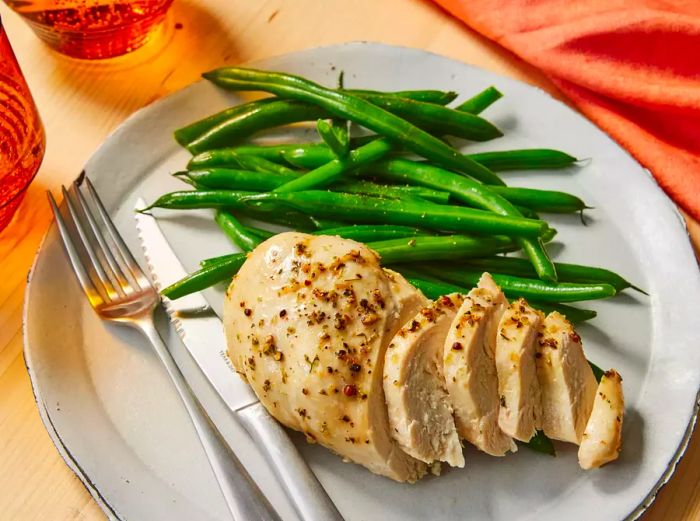 A delicious slice of Italian chicken served alongside fresh green beans.