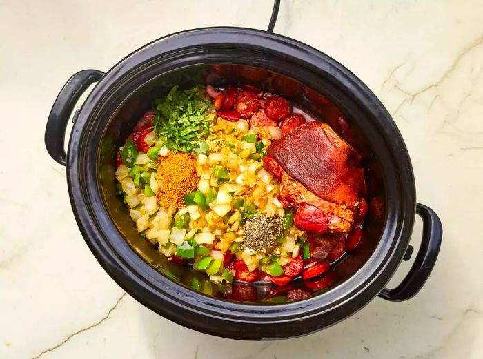 Louisiana Red Beans with meat, vegetables, and seasonings cooking in a slow cooker