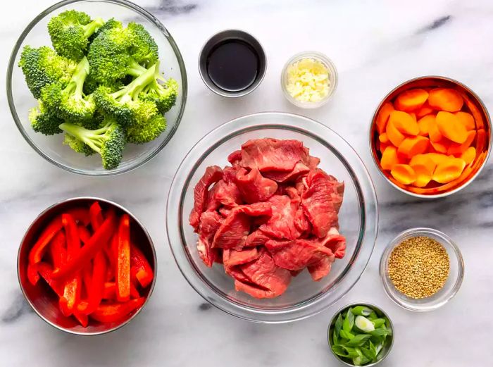 Aerial view of stir-fry ingredients arranged in separate bowls.