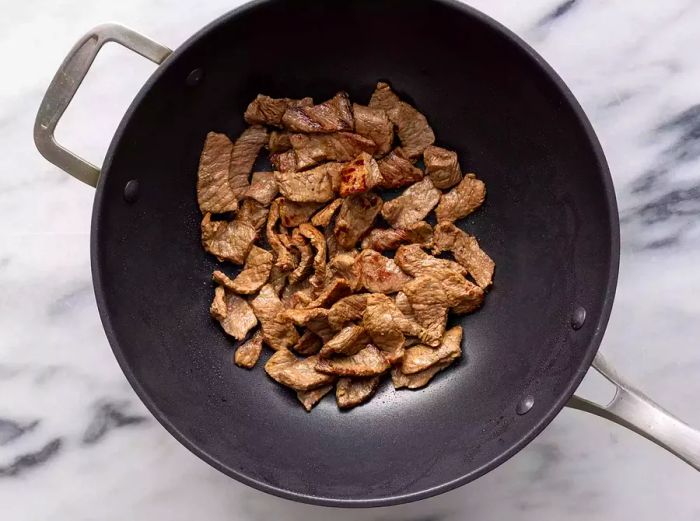 Aerial view of beef cooking in a wok.