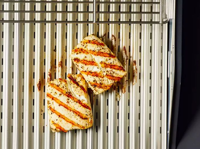 Two grilled halibut fillets on the grill