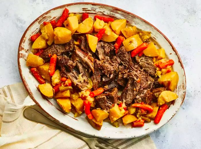 A top-down view of pot roast served on a platter with potatoes and carrots.