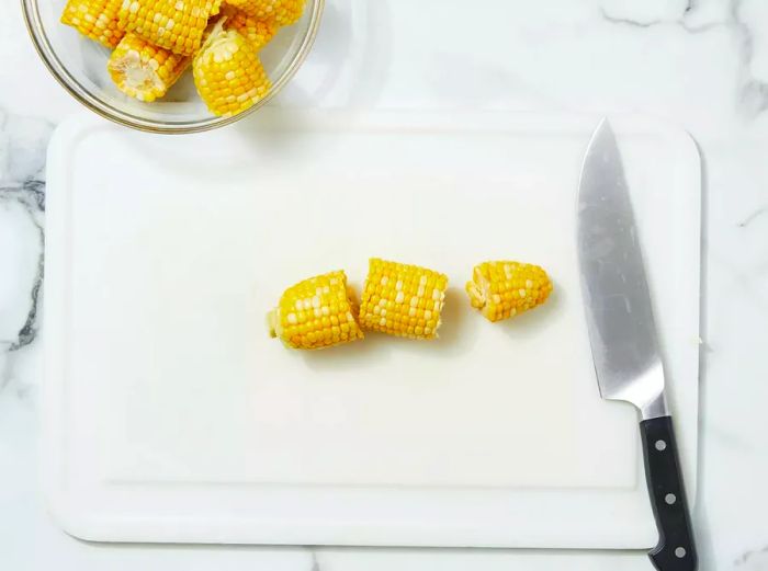 A top-down view of a corn cob being cut into thirds.