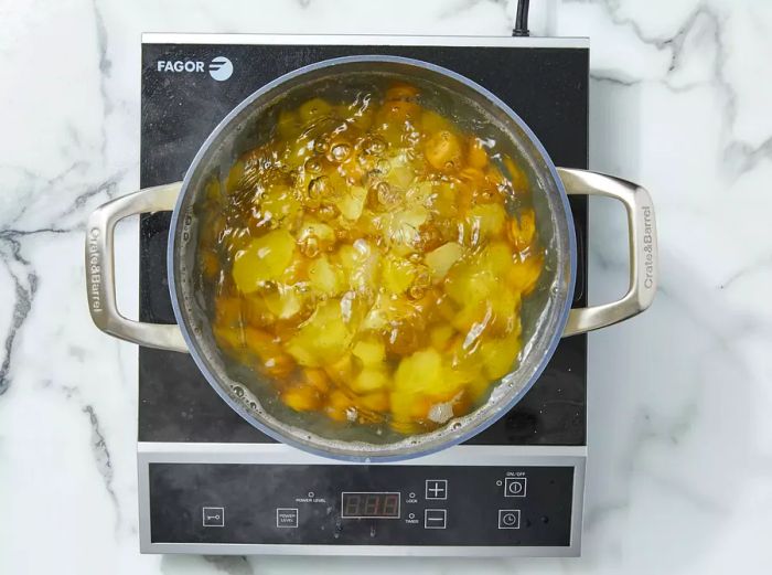 A top-down shot of potatoes cooking in a pot of boiling water.