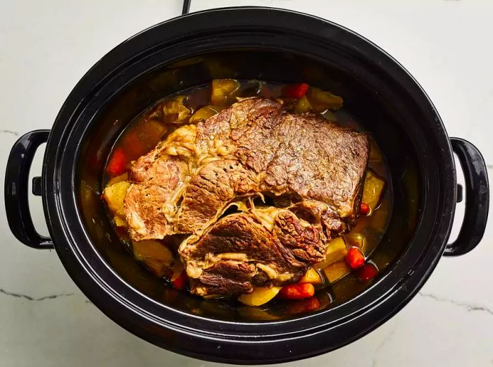 A fully cooked pot roast in the crockpot.