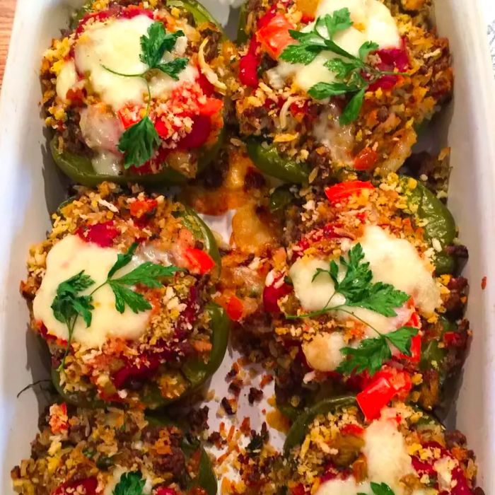 A close-up of stuffed bell peppers garnished with fresh herbs in a white baking dish.