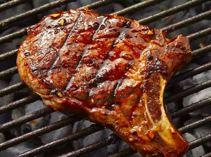 A close-up shot of a perfectly grilled pork loin chop resting on the barbecue