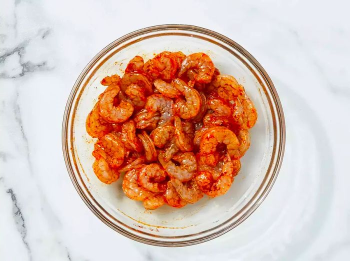 A top-down view of raw shrimp coated with Cajun seasoning.