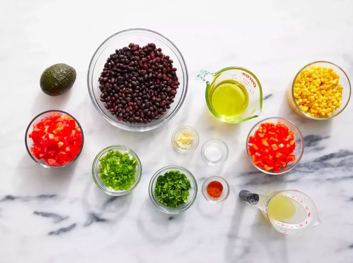 Ingredients for Black Bean and Corn Salad on a marble countertop