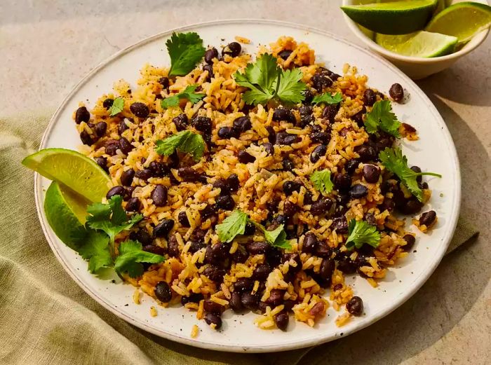 A plate of black beans and rice, garnished with fresh cilantro and lime wedges