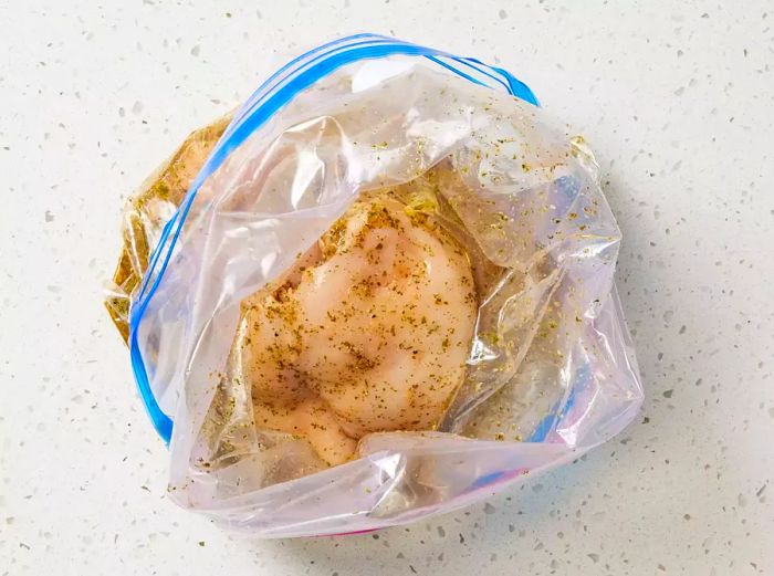 Raw chicken breasts soaking in marinade inside a plastic bag