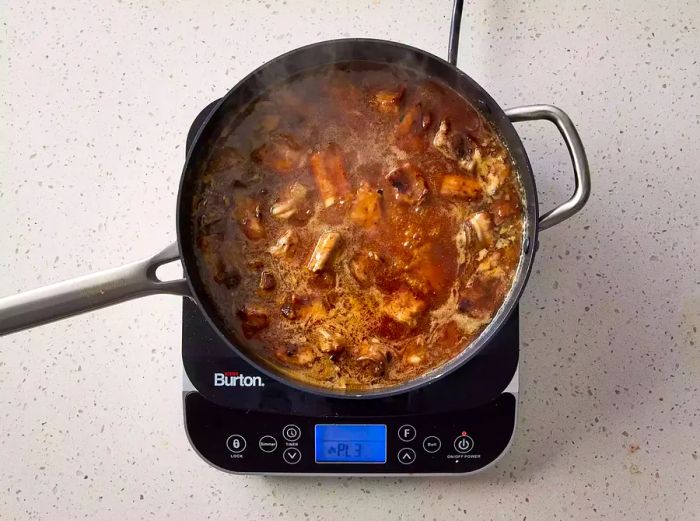 A pan with seared pork spareribs simmering in sweet and sour sauce.