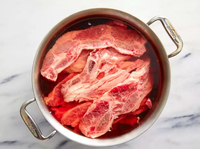 Top-down shot of a large pot filled with beef and liquid