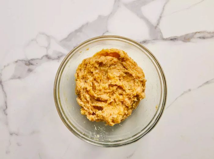 A bowl of seasoned ground chicken ready for shaping.