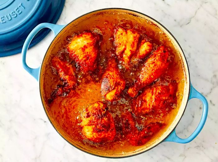 An overhead view of chicken frying in a cast iron skillet filled with sizzling oil.