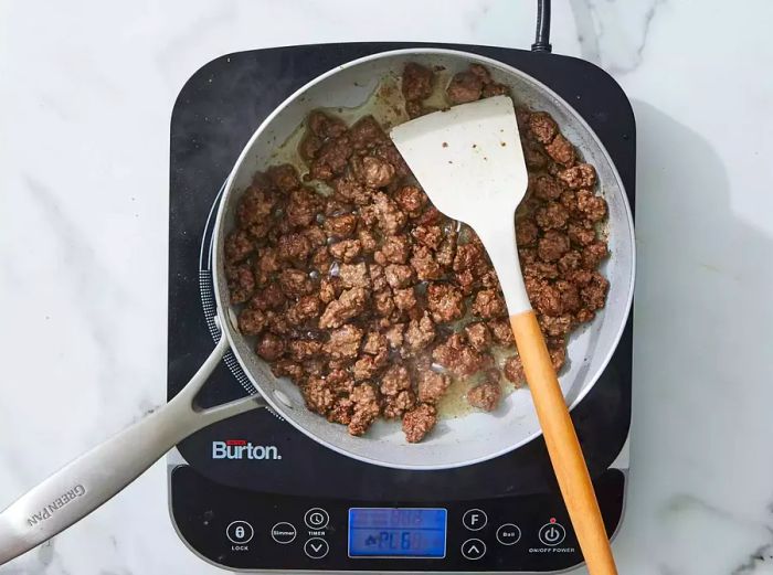 Beef cooking in the skillet until browned and crumbled