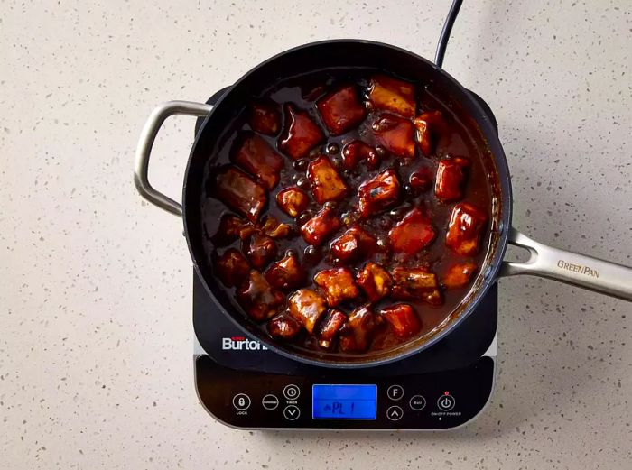 A pan with pork spareribs coated in a thick sweet and sour sauce.